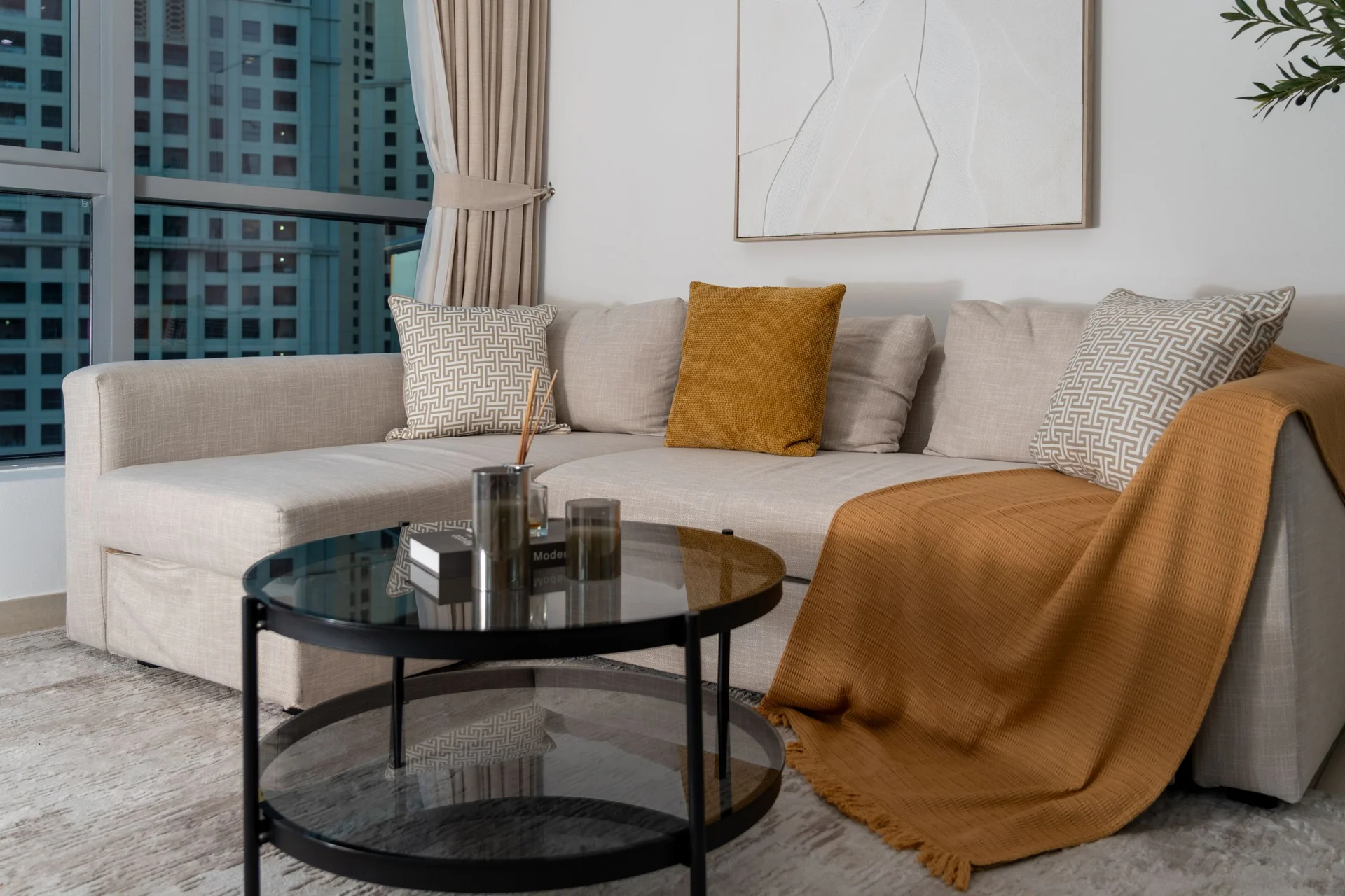 Elegant modern living room with a beige sofa, decorative pillows, and stylish glass coffee table in Dubai.